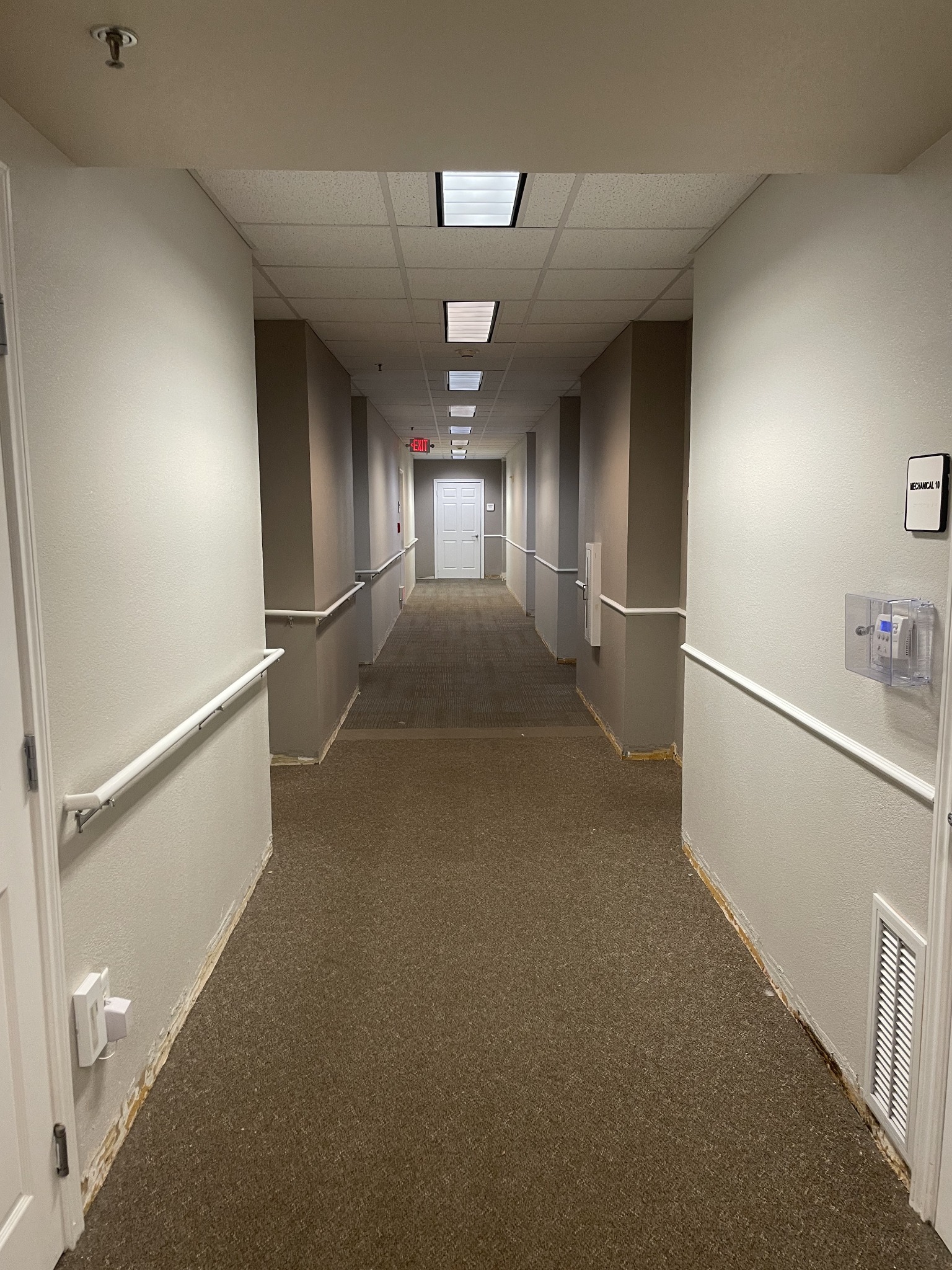 Finished interior hallway with ceiling panels and lighting